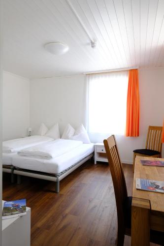 ein Schlafzimmer mit einem Bett und einem Tisch und einem Fenster in der Unterkunft Hotel Frieden in Davos