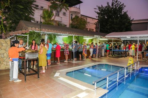 un grupo de personas de pie junto a una piscina en More Hotel, en Beldibi