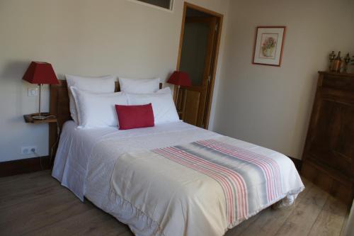 a bedroom with a white bed with a red pillow at Les FREJALS in Compeyre