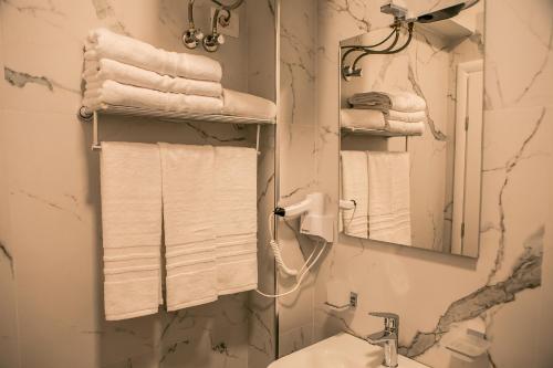 a bathroom with a sink and a mirror and towels at ODA Aparthotel Shkodër in Shkodër