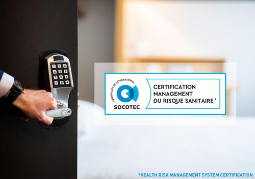 a person holding a remote control in front of a sign at B&B HOTEL Paris Nord Aulnay-sous-Bois in Aulnay-sous-Bois
