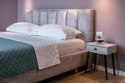 a bedroom with a large bed and a night stand at ODA Aparthotel Shkodër in Shkodër