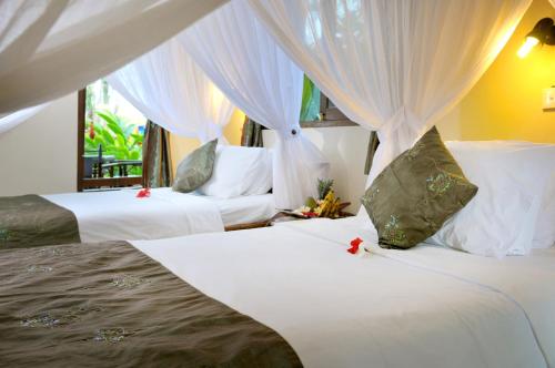 1 dormitorio con 2 camas, sábanas blancas y cortinas en Coral View Villas, en Amed