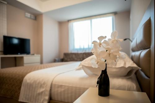 a hotel room with a bed and a vase of flowers on a table at ODA Aparthotel Shkodër in Shkodër