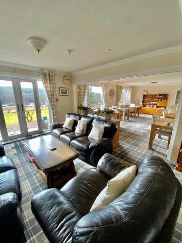 a living room with a leather couch and a table at Coire Glas Guest House in Spean Bridge
