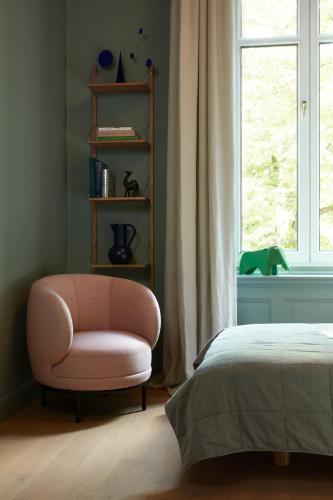 a bedroom with a pink chair and a window at stilwerk Hotel Heimhude in Hamburg