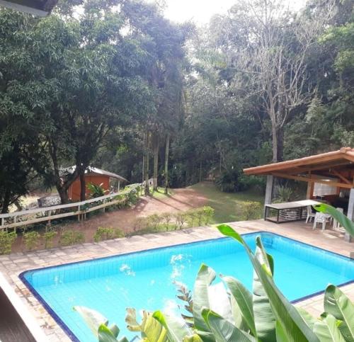 a swimming pool in a resort with trees in the background at Sitio Arco Iris da Lia in São Roque