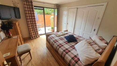 1 dormitorio con 1 cama, TV y ventana en Ardconnel Apartment, en Inverness