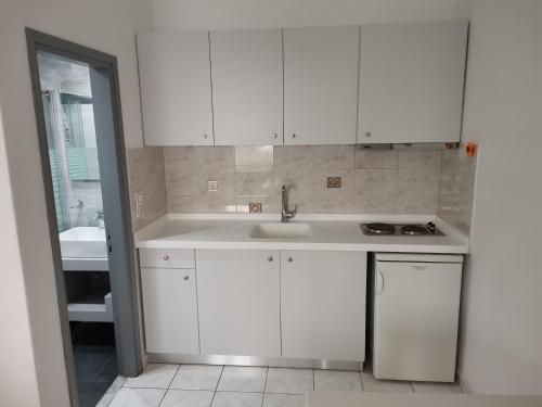 a kitchen with white cabinets and a sink at Venus De Milo in Adamas