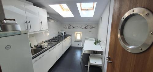 eine Küche mit weißen Schränken, einem Waschbecken und einem Spiegel in der Unterkunft Pentagos Centrum in Posen