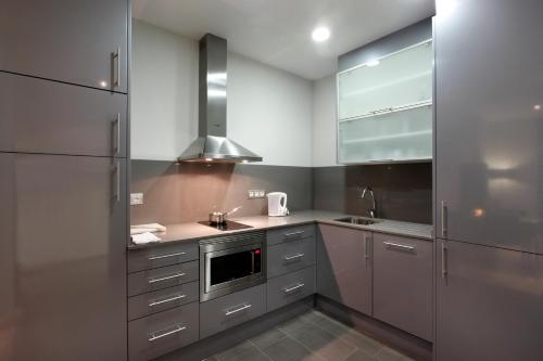 a kitchen with a stainless steel refrigerator, microwave, sink and dishwasher at Fisa Rentals Gran Via Apartments in Barcelona