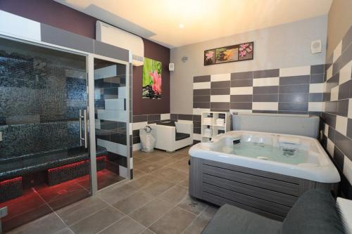 een grote badkamer met een bad en een douche bij The Originals Boutique, Hôtel de l'Univers, Montluçon (Inter-Hotel) in Montluçon