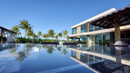 - une piscine en face d'un bâtiment avec des palmiers dans l'établissement Porto Bali Hotel, à Santa Cruz Cabrália
