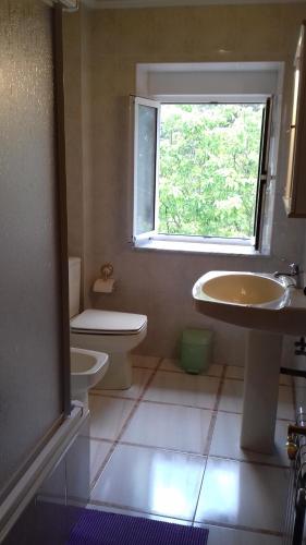 a bathroom with a sink and a toilet and a window at La Coruxa in Los Cabos