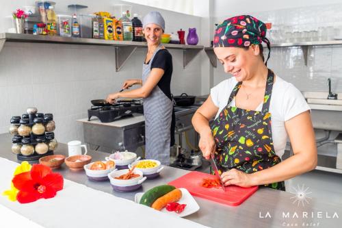 twee vrouwen die in een keuken eten klaarmaken bij Casa Hotel La Mariela in Zapzurro