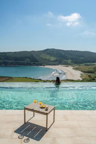 a table in a pool with a view of a beach at Parador Costa da Morte in Muxia