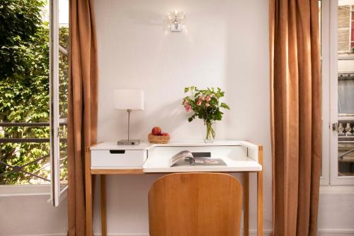 einen Schreibtisch mit einem Waschbecken neben einem Fenster in der Unterkunft Le Hameau de Passy in Paris