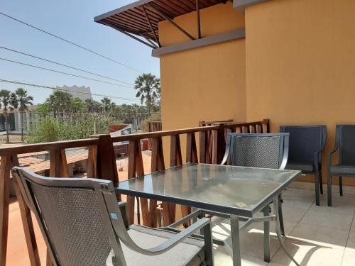 a glass table and chairs on a balcony at Forest View Apartments in Kololi