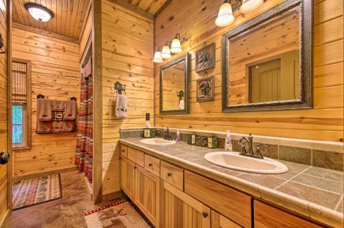 a log cabin bathroom with two sinks and a mirror at Spacious Family Home with Fire Pit by Norfork Lake! in Mountain Home