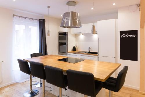 une cuisine avec une table en bois et des chaises noires dans l'établissement Le Faubourg - Apt 3étoiles, Centre Ville, Calme, Spacieux, à Strasbourg