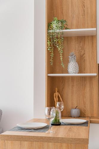 a dining table with two glasses and a pineapple on a shelf at Jacuzzi - Flexible SelfCheckIns 20 - Zagreb - Luxury - Garage - Smart - Brand New - Apartments Repinc in Zagreb