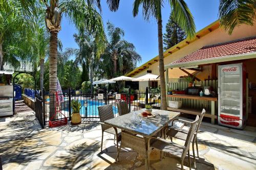 a table and chairs on a patio with palm trees at Out of Africa Resort in Had Nes