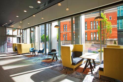 a restaurant with yellow chairs and tables and windows at Holiday Inn Manchester - City Centre by IHG in Manchester