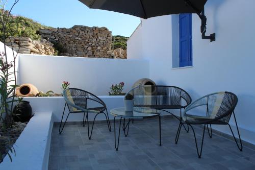 um pátio com 2 cadeiras, uma mesa e um guarda-sol em Cycladic Villa in Amorgos Island (Maison Shiro) em Arkesíni