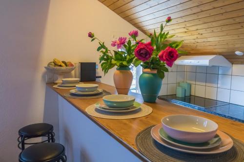 un bancone con piatti e vasi con fiori sopra di Swiss Mountains Apartments a Interlaken