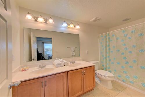 a bathroom with a sink and a toilet and a mirror at 4 Bedroom SunHaven Townhouse with Pool Near Disney in Kissimmee