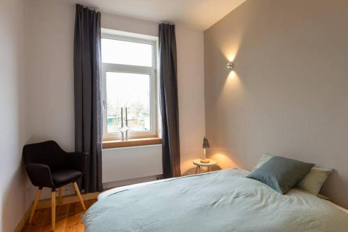 een slaapkamer met een bed, een raam en een stoel bij WERKGUT - charmantes großzügiges Loft im Naturpark in Meezen