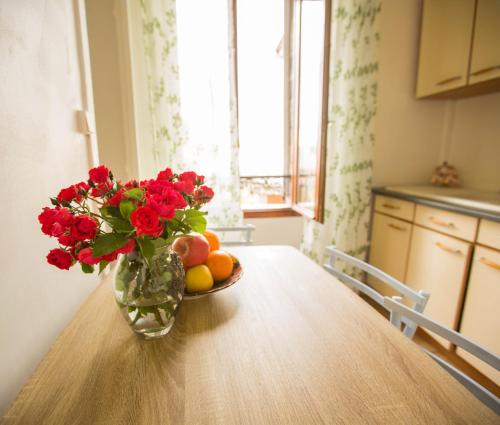 un jarrón con flores rojas y fruta en una mesa en Très sympa appartement à cote de la gare, en Persan