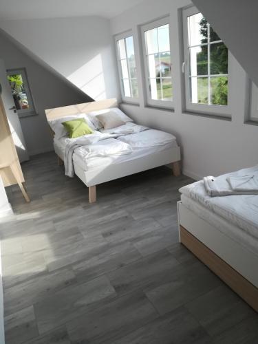 zwei Betten in einem Zimmer mit Holzboden und Fenstern in der Unterkunft Armona in Ustka