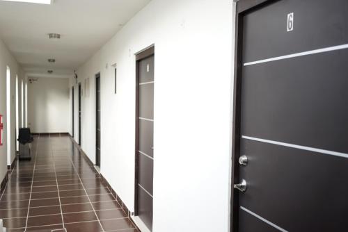 - un couloir avec une porte noire et du carrelage dans l'établissement Hotel Diez, à Tampico