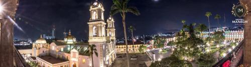 a large building with a clock tower at night at Hotel Mansur Business & Leisure in Córdoba