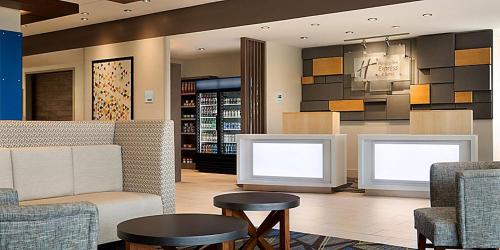 a lobby with two chairs and a couch and tables at Holiday Inn Express & Suites - Kokomo South by IHG in Kokomo