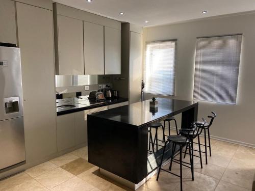 a kitchen with a black counter and stools at The Franklin Luxury Apartments in Johannesburg
