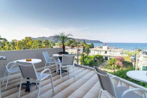 balcone con tavoli, sedie e vista sull'oceano di Abella Hotel ad Agia Marina Nea Kydonias