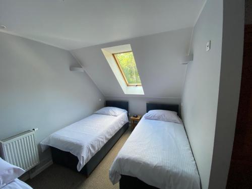 two beds in a small room with a window at Aulichówka - Dom Wakacyjny i Squash in Gryżyna