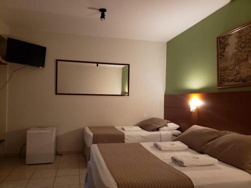 a hotel room with two beds and a mirror at Proença Hotel in Barretos