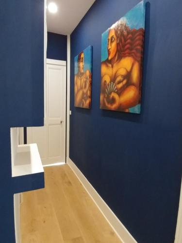 un couloir avec trois peintures sur un mur bleu dans l'établissement Confort douceur et calme dans Grenoble, à Grenoble