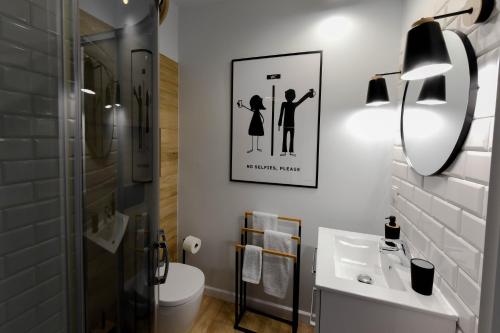 a bathroom with a toilet and a picture of a couple at Aulichówka - Dom Wakacyjny i Squash in Gryżyna