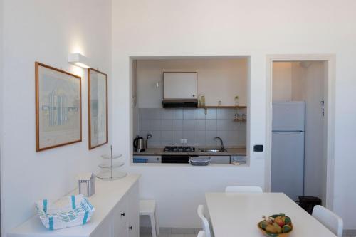 a white kitchen with a table and a counter top at Casa Blu sul mare e centralissima in San Vito lo Capo