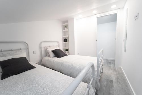 a white bedroom with two beds and a mirror at Buhardilla Comillas Beach en Primera Línea de Playa, Wifi, Netflix in Comillas