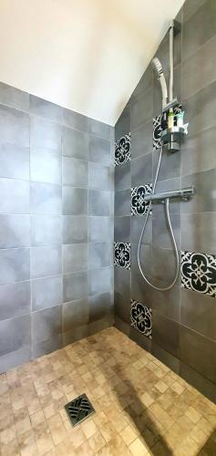 La salle de bains est pourvue d'une douche et d'un mur en carrelage. dans l'établissement villa calme et detente, à Montbolo