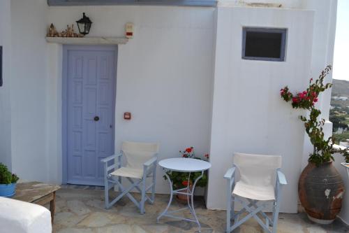 a patio with two chairs and a table and a door at Studio Ioanna Tinos in Kionia