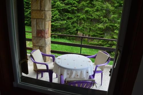 a table and chairs on a porch with a window at Vila Mira Zlatar in Nova Varoš