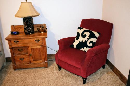 a red chair sitting next to a table with a lamp at Iowa House Historic Inn in Ames
