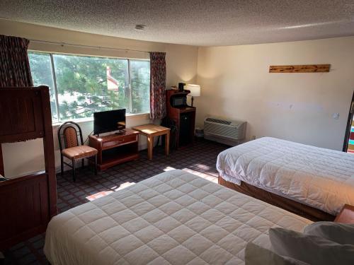 Una habitación de hotel con dos camas, un escritorio y una ventana. en Ventura Grand Inn, en Mammoth Lakes
