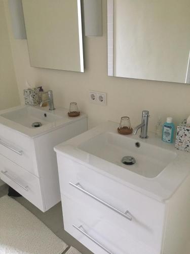 a white bathroom with two sinks and a mirror at Retour de Provence in Almelo